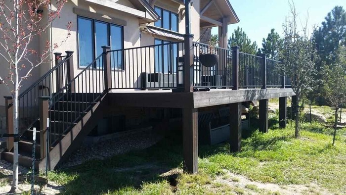 A deck with a railing and stairs in front of a house.