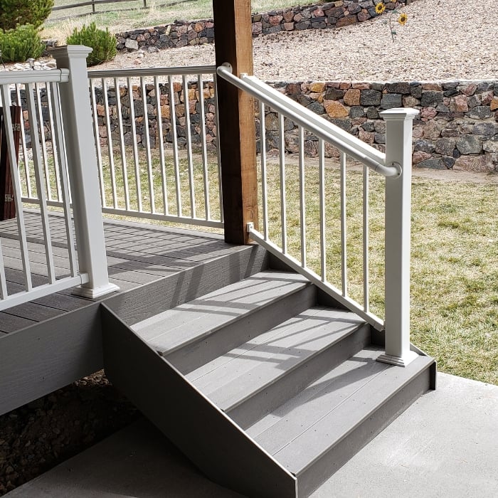Grey Deck Staircase with Grey Railing and Stone Wall in Background