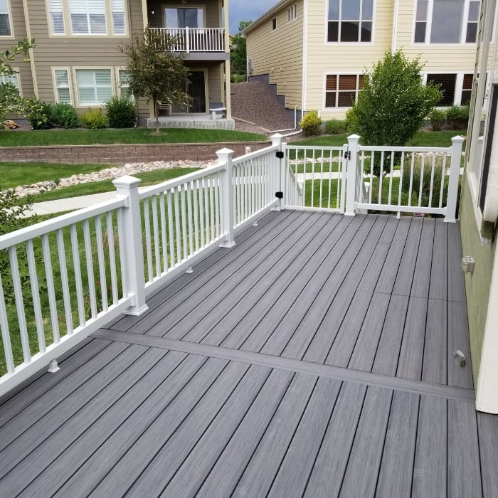 Grey Deck with White Railing Overlooking Backyard and Other Houses