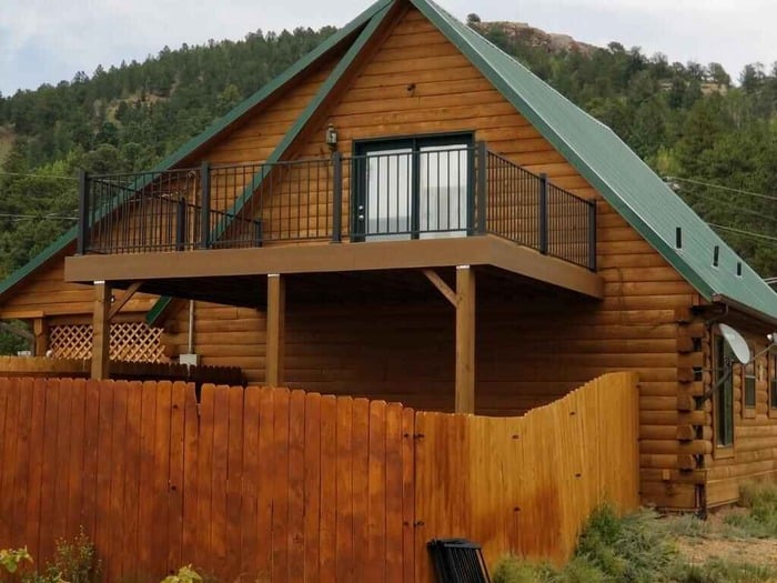 A log cabin in the mountains with a balcony.